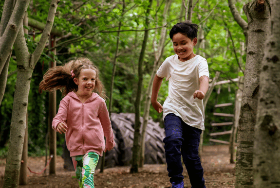 Kids playing in the woodland playground at Airfield Estate